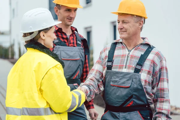 Builder and contractor on construction site shaking hands in acceptance — Stock Photo, Image