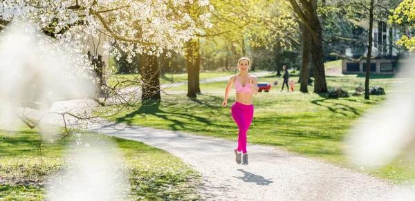 Fitte Frau läuft im Frühling durch Blüte einen Pfad hinunter — Stockfoto