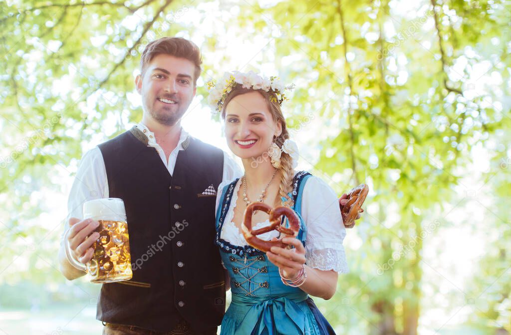 Bavarian couple in Tracht toasting with beer