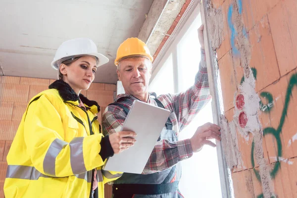 Travailleur de la construction vérifie un mur de panneau de fenêtre avec ingénieur en utilisant une tablette numérique — Photo