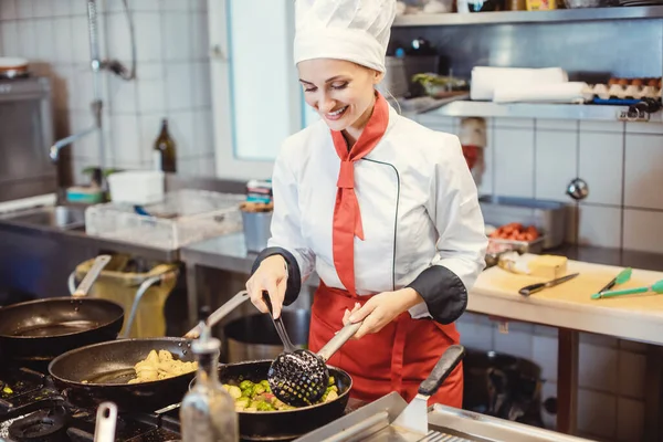 Vrouwelijke chef-kok met pannen en potten bereidt eten in de keuken van het restaurant — Stockfoto