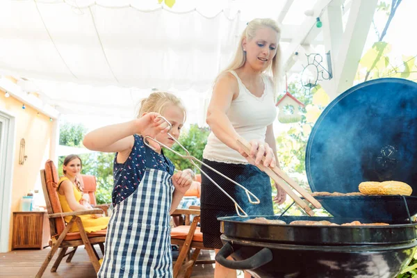Mom and daughter at the grill doing the barbeque — Stock Photo, Image