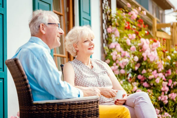 Senior couple enjoying their coffee on porch in front of their house — Stock Photo, Image