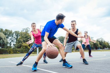 Basketball players playing at outdoors court clipart