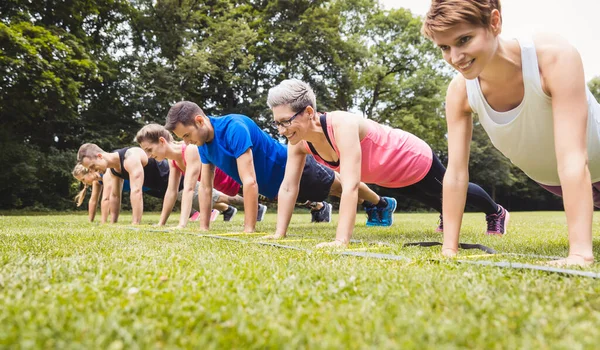 Fitness groep oefent push-ups in het park — Stockfoto