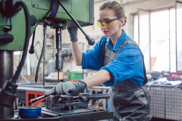 Vrouwelijke werkneemster in metaalwerkplaats smeerboor — Stockfoto