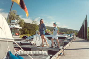 Anne ve oğlu limanda oturan bir tekneye biniyor.