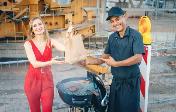 Кухаря дає жінці клієнт бургер в сумці для виводу — стокове фото