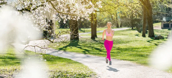 Fit vrouw loopt een pad in het voorjaar gezien door bloesem — Stockfoto