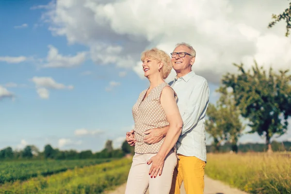Seniorenpaar blickt in Sommerlandschaft gemeinsam in die Zukunft — Stockfoto
