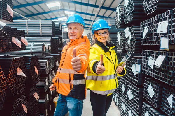 Dělnický tým ve skladu ocelářství ukazující palce nahoru — Stock fotografie