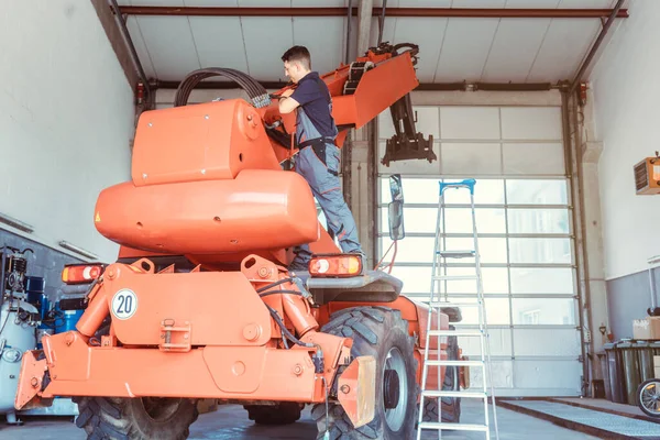 Machinist reparar uma enorme máquina de fazenda em sua garagem — Fotografia de Stock