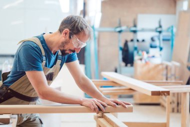 Marangoz ahşabı elle zımparalıyor.