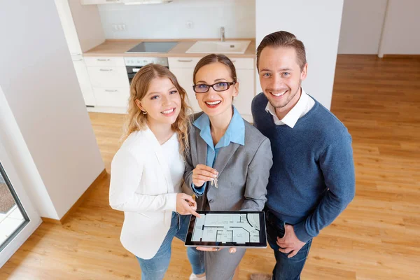 Huis makelaar en klanten in nieuw appartement op zoek naar camera — Stockfoto