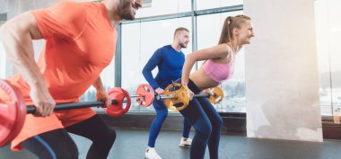 Spor salonunda halterli insanlar pazı kaslarını çalıştırıyorlar.