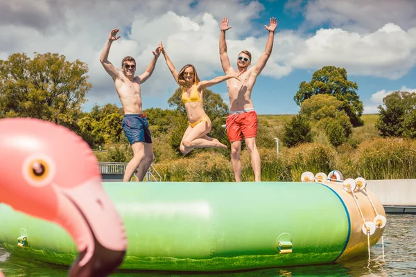 Friends having fun jumping off ein tuby dinghy sache im öffentlich pool — Stockfoto