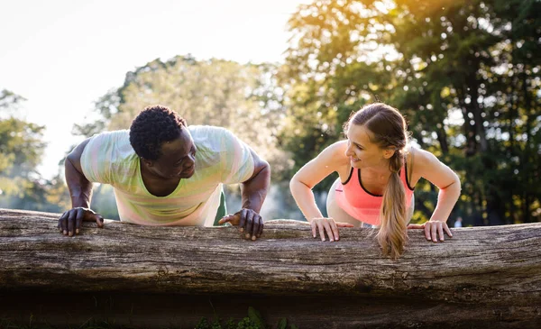 Vrouw en haar fitness coach doen push-ups op boom kofferbak in de zomer — Stockfoto