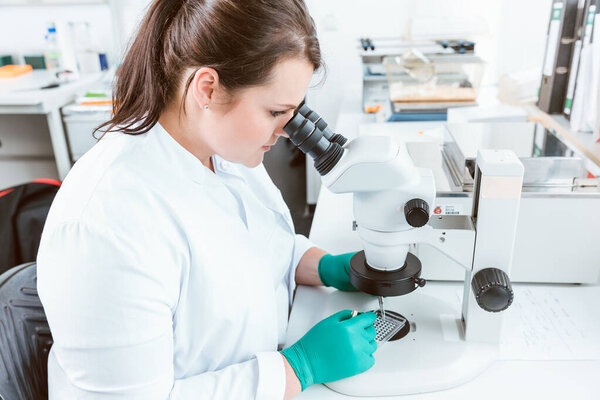 Woman researcher using microscope in lab