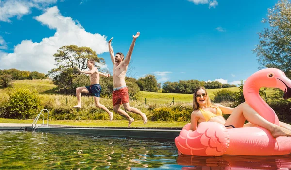 Amici che saltano in acqua della piscina pubblica in estate — Foto Stock