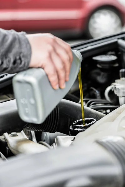 Woman putting oil into the engine of her car — Stock Photo, Image