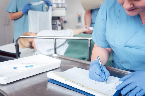 Медсестра пише попередній звіт про операцію на файлі — стокове фото