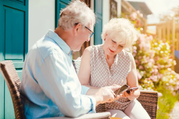 Старшая пара смотрит на свой телефон в саду — стоковое фото