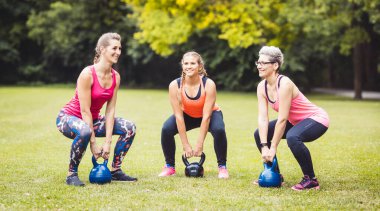 Women doing exercise with kettle bell in park