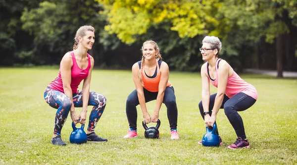 Women doing exercise with kettle bell in park — Foto de Stock