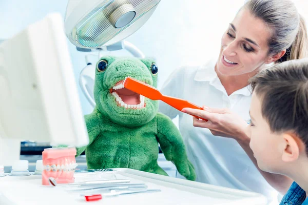 Chlapec při pohledu na doktora čistí dinosauři zuby na klinice — Stock fotografie