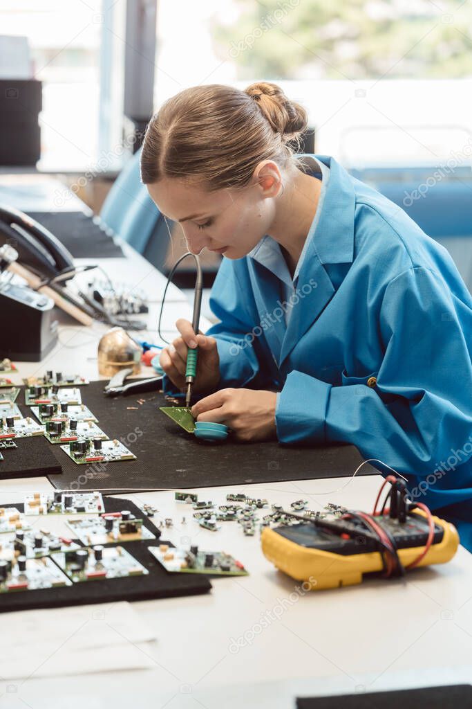 Worker in electronics manufacturing soldering a component