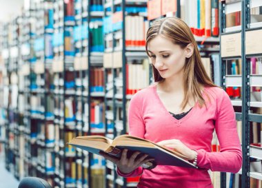 Üniversite kütüphanesinde kitap okuyan bir öğrenci.