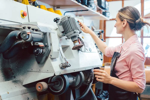 Mujer zapatera trabajando en la máquina en su taller de zapatero — Foto de Stock