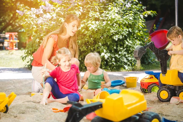Children and play school teacher enjoying some time in sand box — Stock Photo, Image