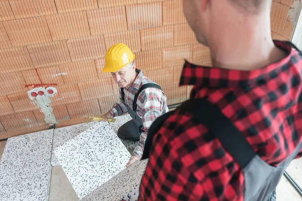 Senior männlicher Bauarbeiter repariert die Fliesen — Stockfoto