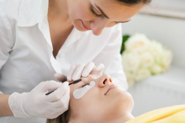 Kadın müşteriye kirpik tedavisi uygulayan kozmetikçi
