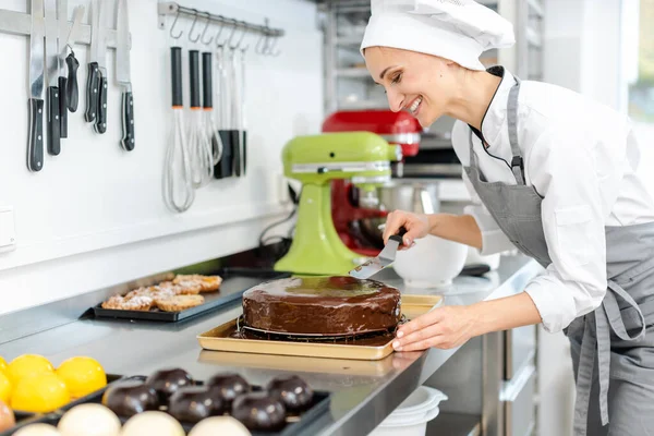 Patissier gießt flüssige Schokolade auf einen Kuchen — Stockfoto