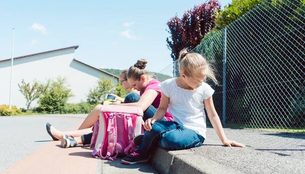 Tre flickor framför skolan väntar på bussen — Stockfoto