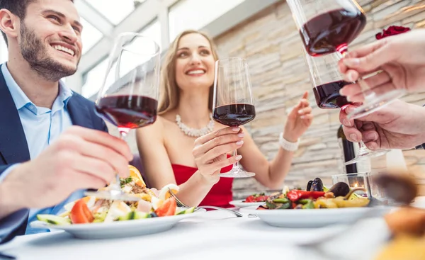 Amigos en un restaurante de lujo tostando con vino tinto italiano —  Fotos de Stock