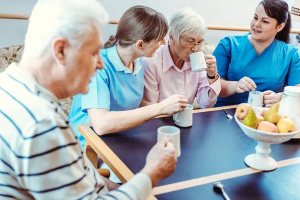 Ηλικιωμένοι και φροντιστές που πίνουν καφέ στο γηροκομείο — Φωτογραφία Αρχείου