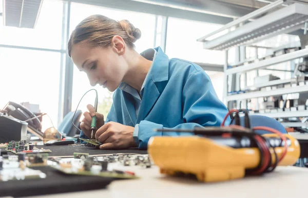 Elektronik üretiminde çalışan bir işçi bir bileşen lehimliyor — Stok fotoğraf