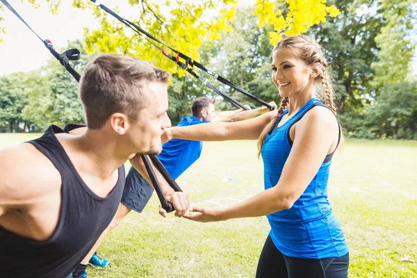 Vrouwelijke trainer begeleidt de man bij het trainen met een weerstandsband — Stockfoto