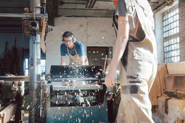 Equipe de carpinteiros planejando madeira usando uma máquina — Fotografia de Stock