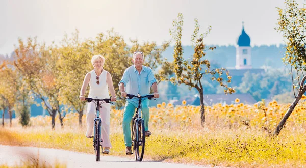 Старшая пара, женщина и мужчина, катаются на велосипедах — стоковое фото