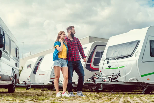 Woman and man choosing camper van to rent or buy