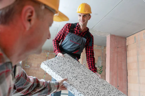 Gelukkige mannelijke werknemers met keramische blok op de bouwplaats — Stockfoto