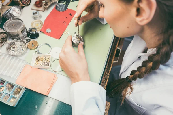 Woman watchmaker working diligently on repairing a watch — Stock Photo, Image