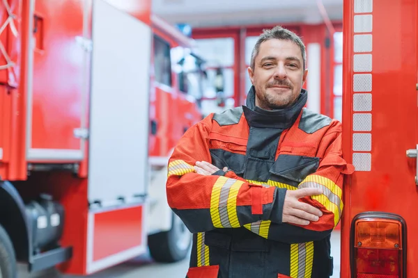 Έμπειρος πυροσβέστης στέκεται μπροστά από πυροσβεστικό όχημα — Φωτογραφία Αρχείου