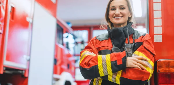 Mulher bombeiro em pé na frente de um caminhão de bombeiros — Fotografia de Stock