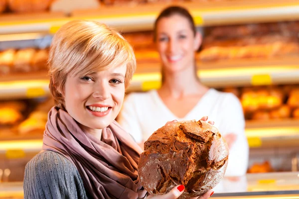 Verkoper met vrouwelijke klant in bakkerij — Stockfoto