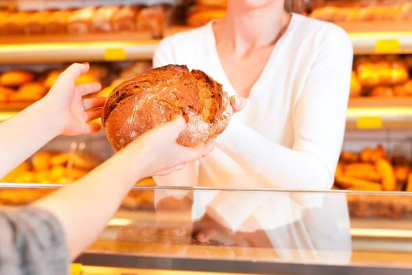 Commerciante con cliente femminile in panetteria — Foto Stock